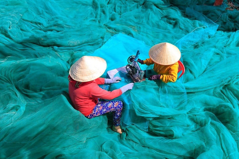 Dos mujeres están cosiendo las redes de pesca en Vietnam