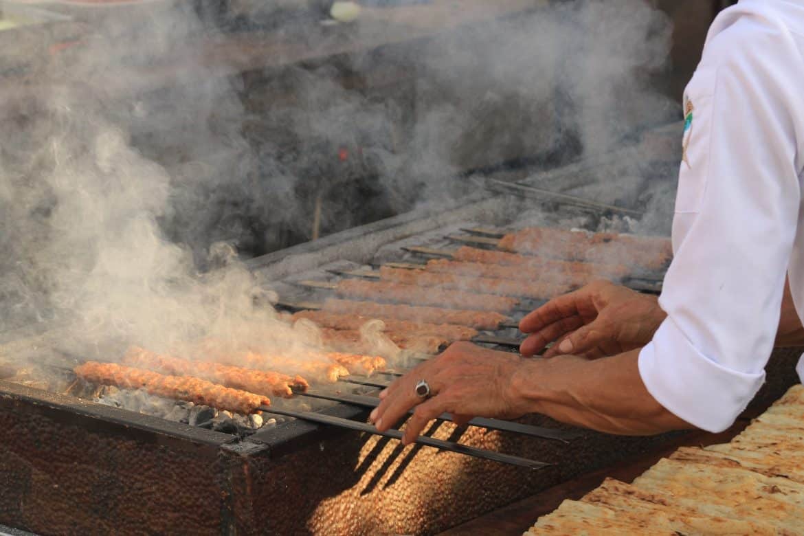 Cocineros turcos preparando variedades distintas de kebabs a la parrilla